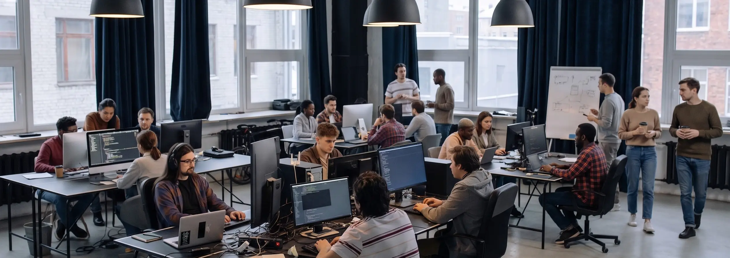 Equipo de desarrollo de software trabajando en una oficina abierta con pantallas de código